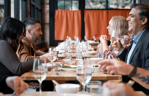 A group of people smiling and chatting over dinner at a large table