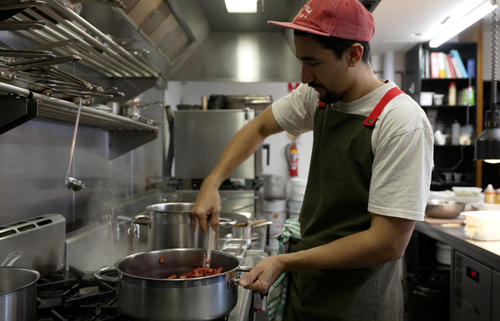 Chef mixing food in a pot in the back kitchen of a restaurant