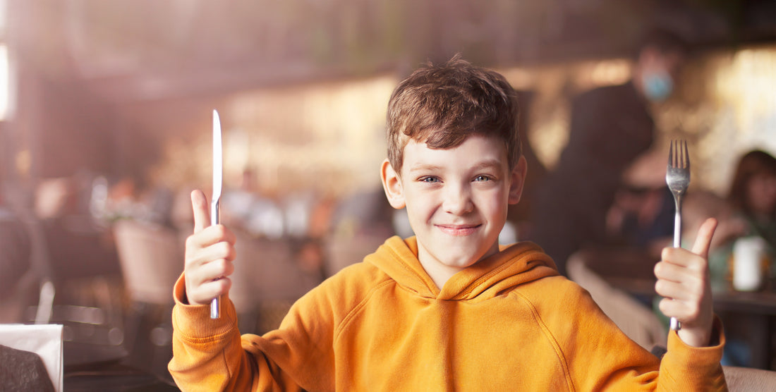 Boy with cutlery in his hands is ready to eat