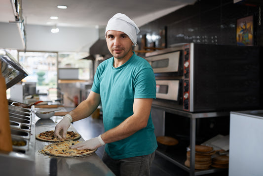 A chef making pizza on a pizza prep table